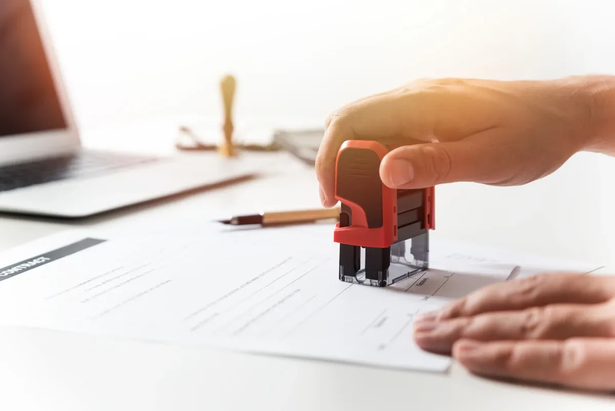 Foto zeigt eine Hand, die gerade ein Dokument stempelt